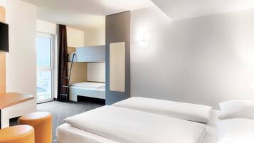 Ein modernes Hotelzimmer mit einem Etagenbett, einem Schreibtisch und zwei Poufs.