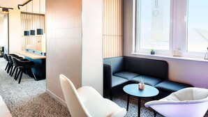 A modern lounge area with a seating arrangement including a sofa, chairs, and a small table. - B&B Hotel Emden (Emden)