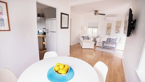 En moderne stue med spiseplads, med en hvid sofa, et sofabord og en skål med citroner på bordet.