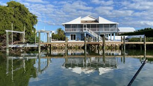 Une propriété située au bord de l’eau, avec une maison à deux étages, un quai et un ciel dégagé.