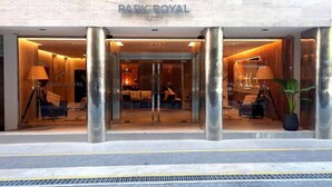 A hotel entrance with a modern design, featuring a glass facade, large pillars, and a welcoming interior with seating and a piano. - Impeccable Junior Suite with Gym in Buenos Aires (Buenos Aires)