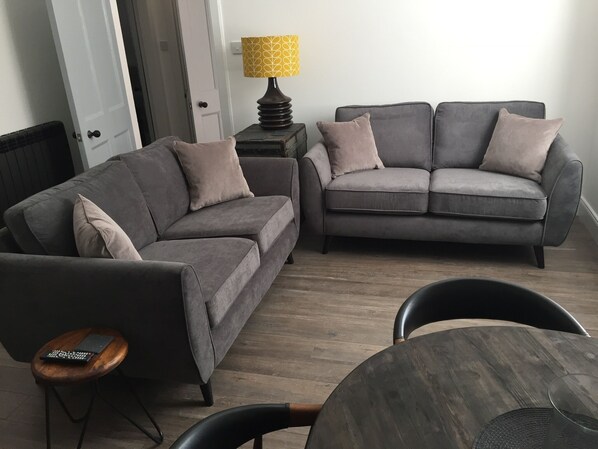 A living room with two grey sofas, a wooden coffee table, and a small side table with a lamp.