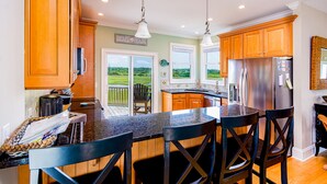 A kitchen with wooden cabinets, a stainless steel refrigerator, and a large island with bar stools. - "Cool Fish" - 2nd Row Home w/ Private Pool, 5 Bedrooms / 4.5 Bathrooms (Holden Beach)