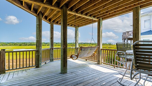 A wooden deck with a hammock and metal chairs, overlooking a green landscape. - "Cool Fish" - 2nd Row Home w/ Private Pool, 5 Bedrooms / 4.5 Bathrooms (Holden Beach)