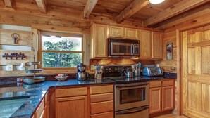 Une cuisine avec des meubles en bois, un four à micro-ondes en acier inoxydable, une cuisinière et une grande fenêtre.