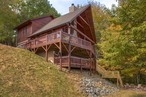 Eine zweistöckige Blockhütte mit Balkon und einer Treppe, die zum Obergeschoss führt.