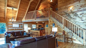 Une cabane spacieuse dotée d’un grand espace de vie, d’une cuisine et d’un escalier menant à une mezzanine.