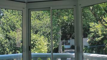 A room with a view of a balcony and trees.