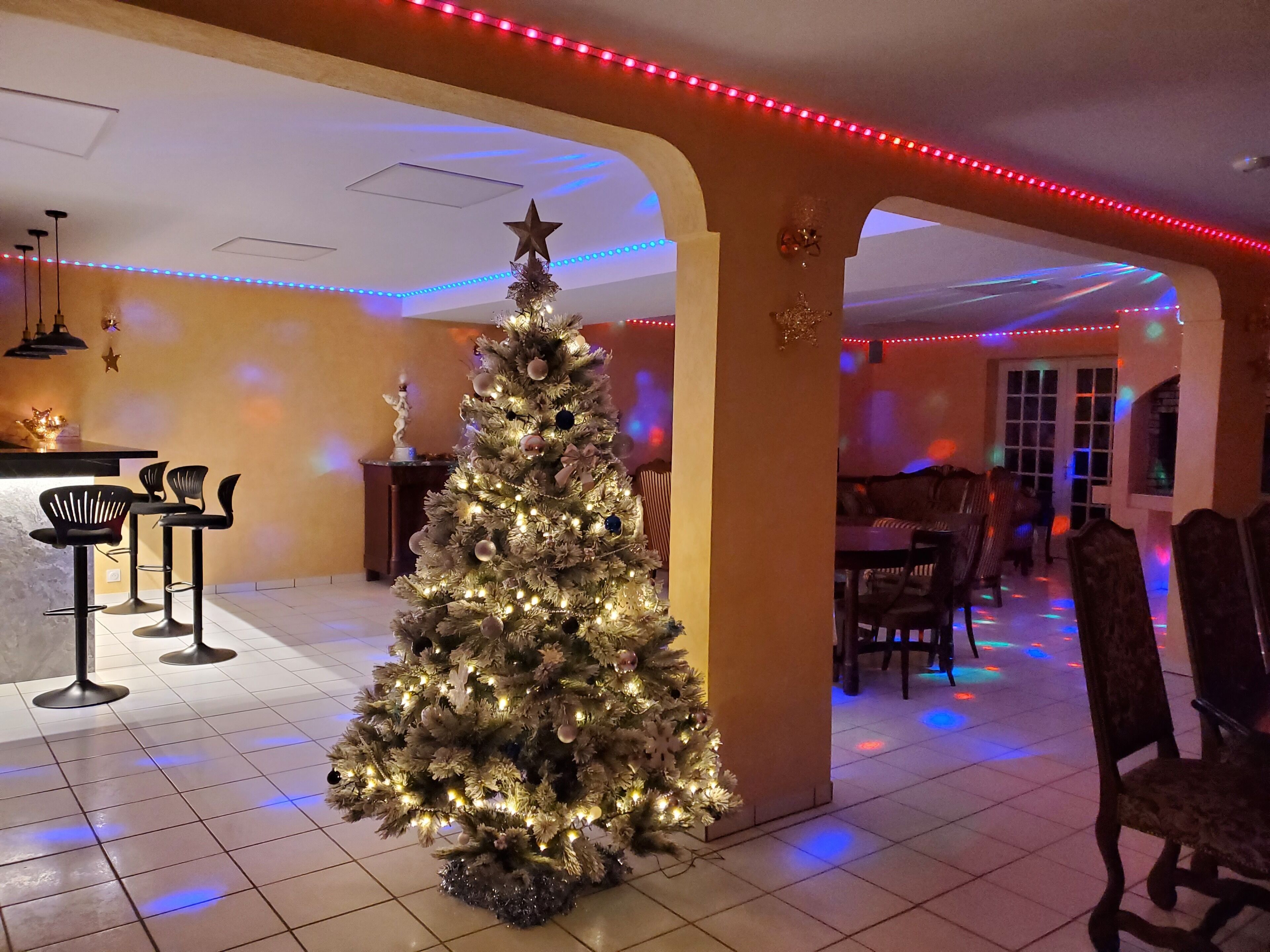 Ein Weihnachtsbaum in einem Essbereich mit Fliesenboden, Barhocker und einem Tisch.