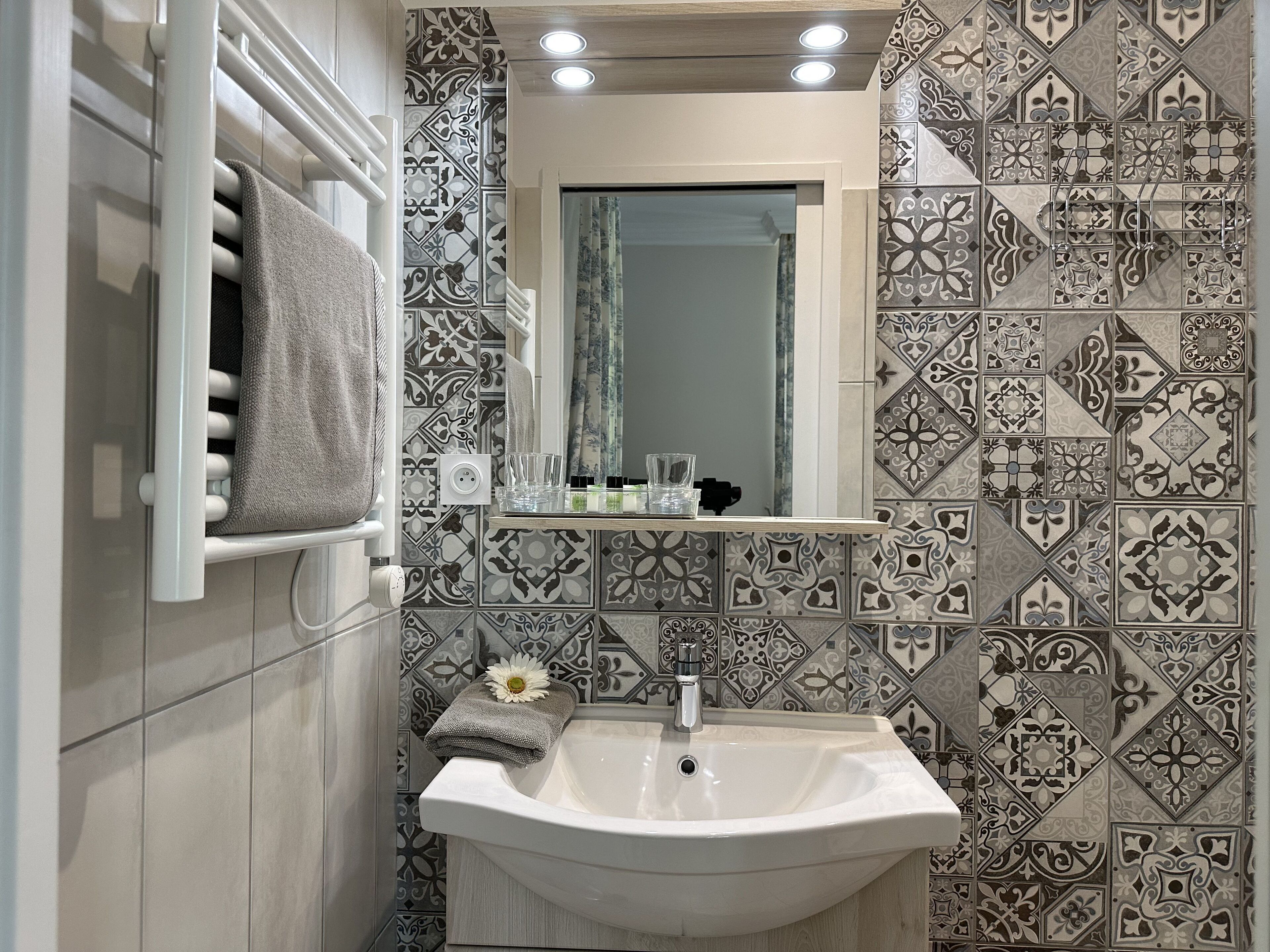 A bathroom with a white sink, a towel rack, and patterned tiles.