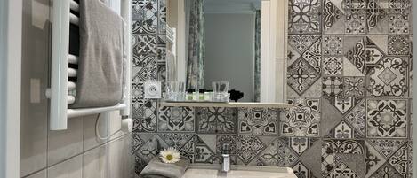 A bathroom with a white sink, a towel rack, and patterned tiles.