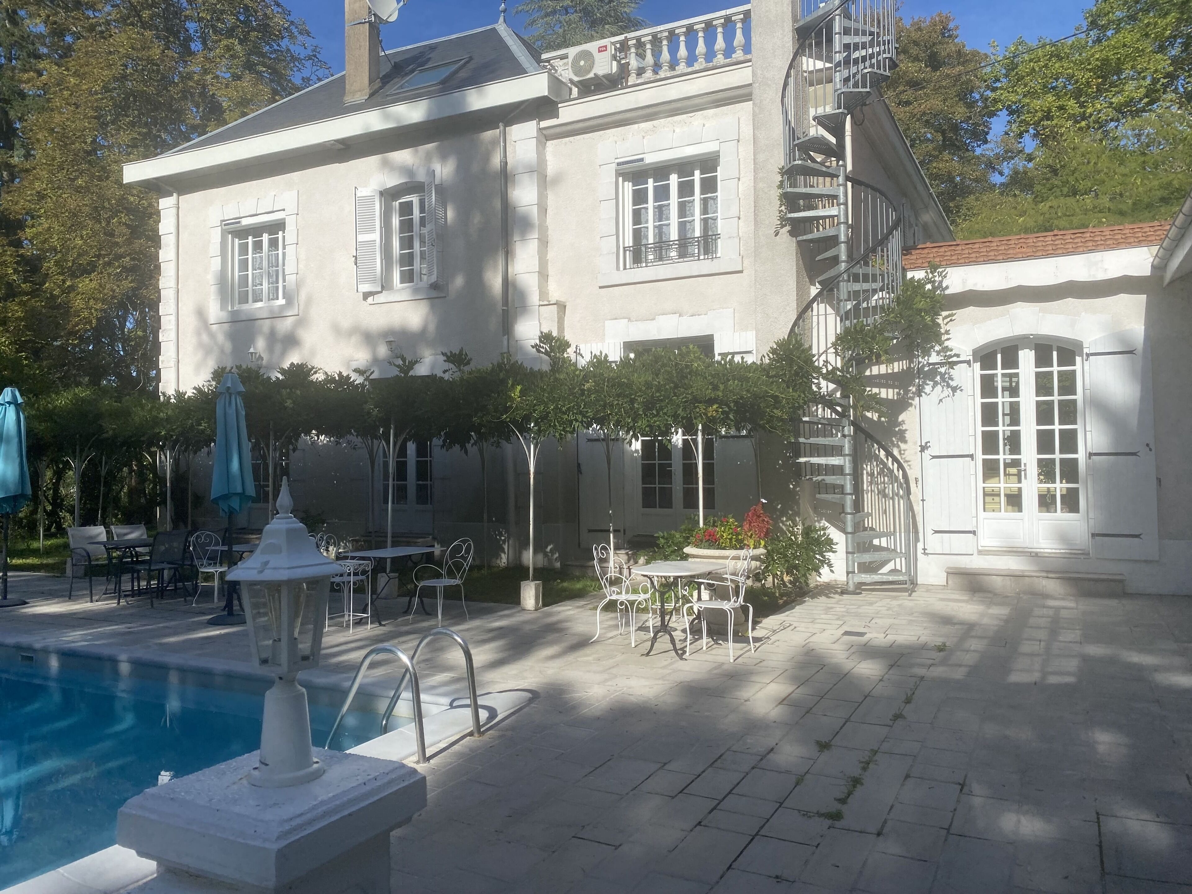 A large building with a pool, outdoor seating, and a spiral staircase.