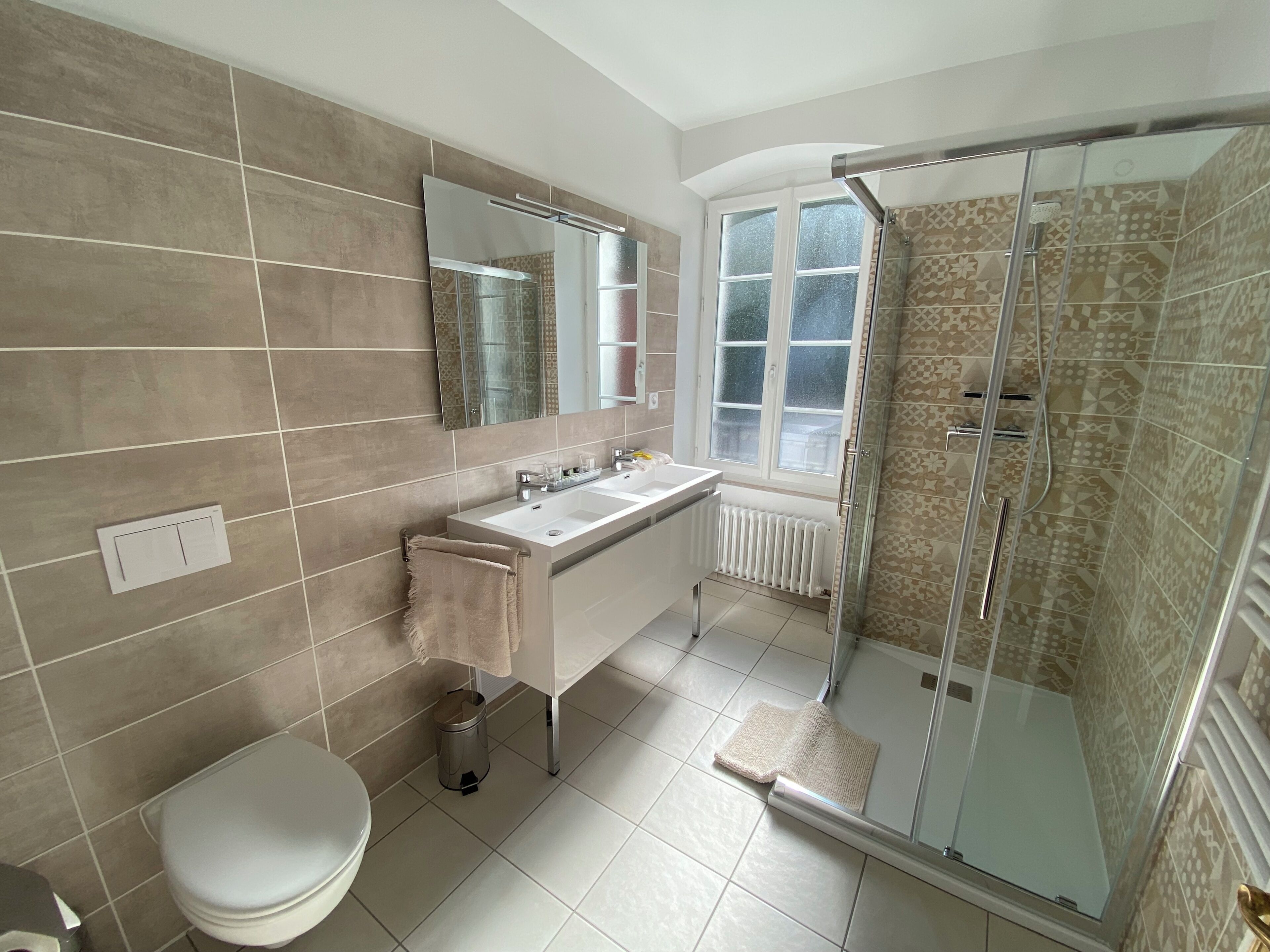 Un baño moderno con inodoro, lavamanos, espejo y ducha.