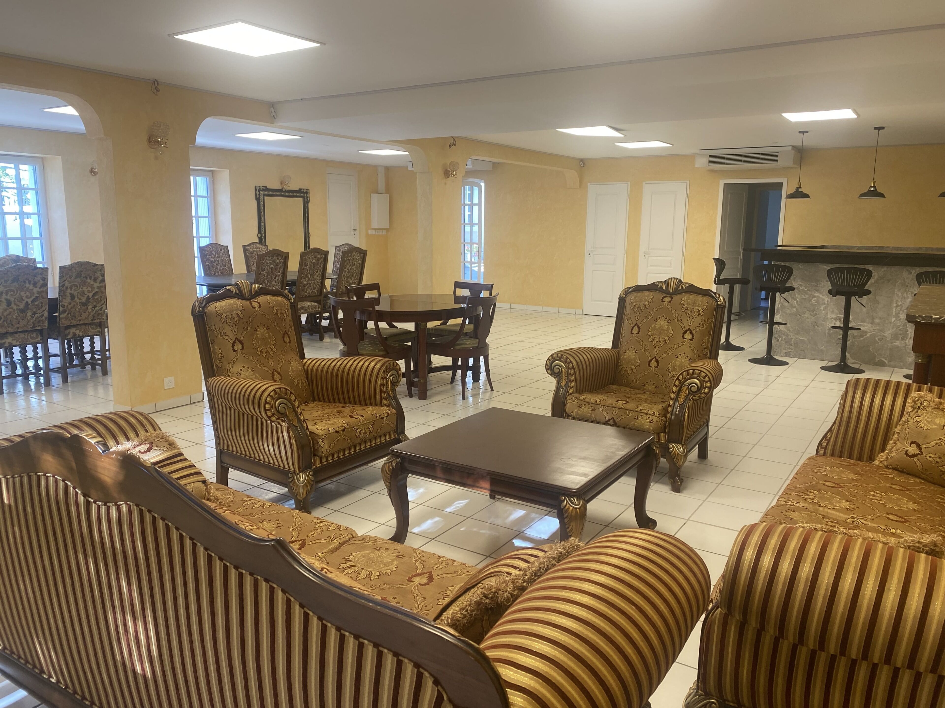 A spacious lobby with classic furniture, a dining area, and a bar.