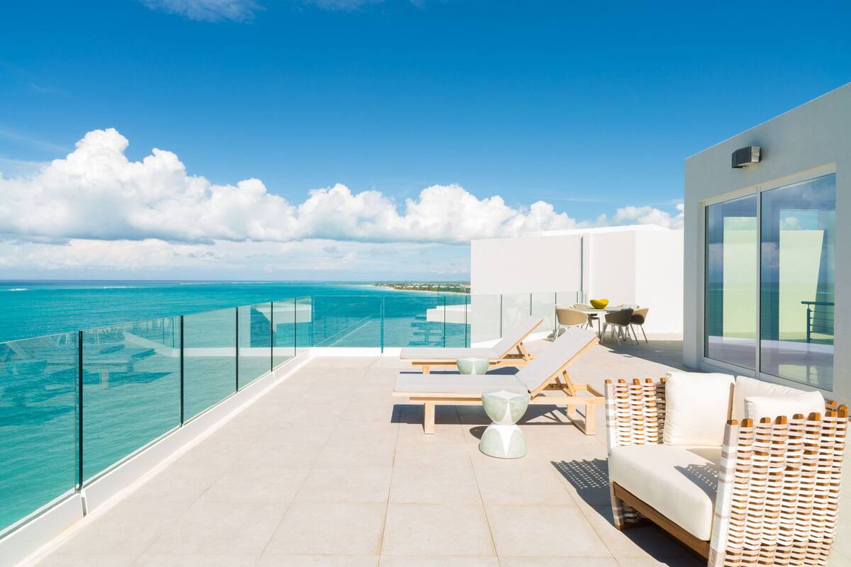 Ein Balkon mit Blick auf das Meer, Liegestühle und ein Tisch mit Stühlen.