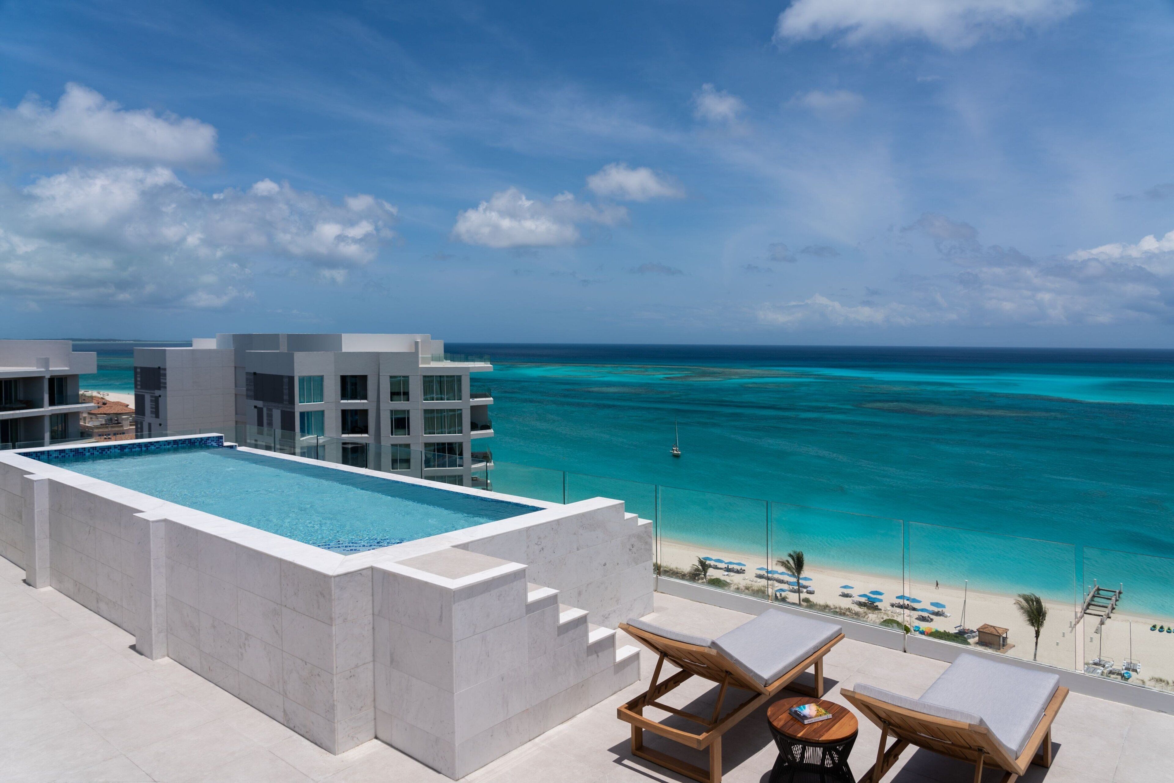 A rooftop pool with lounge chairs and a view of the ocean.