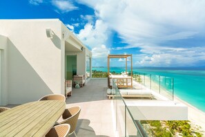 A modern outdoor terrace with a glass balustrade overlooking a beach.