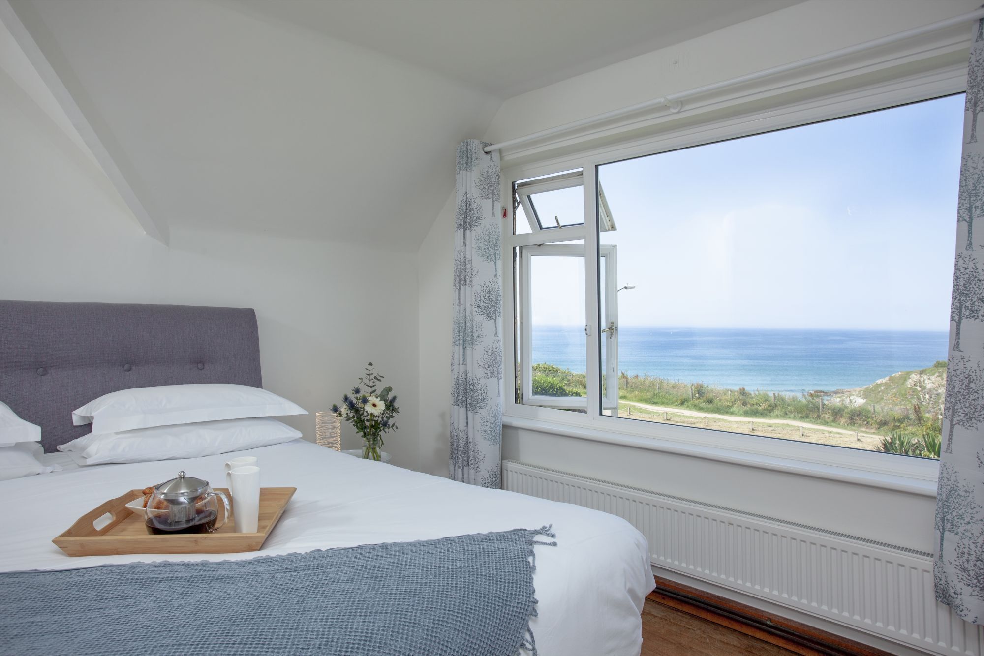 A bedroom with a large window offering a view of the sea.