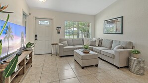 Ein Wohnzimmer mit beiger Couch, Couchtisch, Fernseher und Deckenventilator.