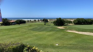 A golf course with a clear view of the ocean and a flagpole.