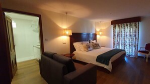 A hotel room with a bed, a sofa, a chair, and a TV.