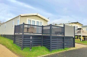 A mobile home with a fenced deck, a small porch, and a satellite dish.