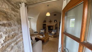 A cozy living area with a fireplace, comfortable seating, and a stone wall. - Charming cottage "La Caussenarde (Saint-Beauzély)