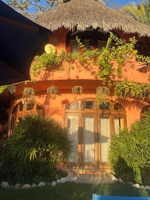 A house with a thatched roof, a wooden door, and potted plants. - Great ocean views, walking distance to town/ beach, heated pool, family friendly (Sayulita)