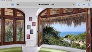 A room with a curved bench, wooden doors, and a view of the ocean. - Great ocean views, walking distance to town/ beach, heated pool, family friendly (Sayulita)