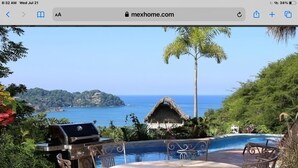 A patio with a grill, a round table, and chairs, overlooking a pool and the ocean. - Great ocean views, walking distance to town/ beach, heated pool, family friendly (Sayulita)