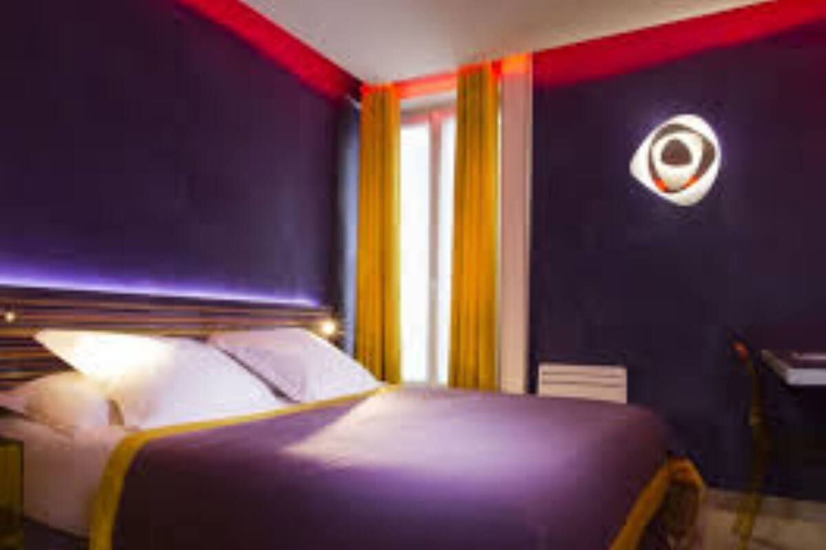 A modern hotel room with a large bed, a desk, and a window with curtains.