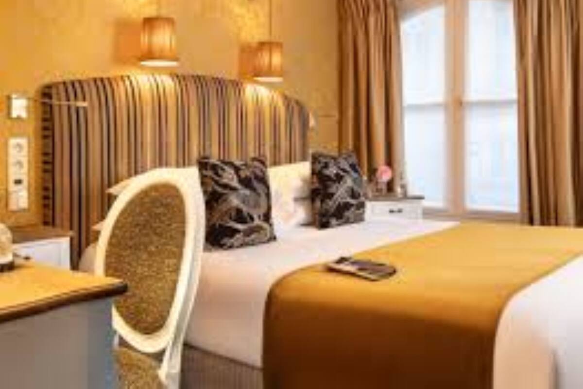 A hotel room with a large bed, two bedside lamps, a nightstand, and a window with curtains.