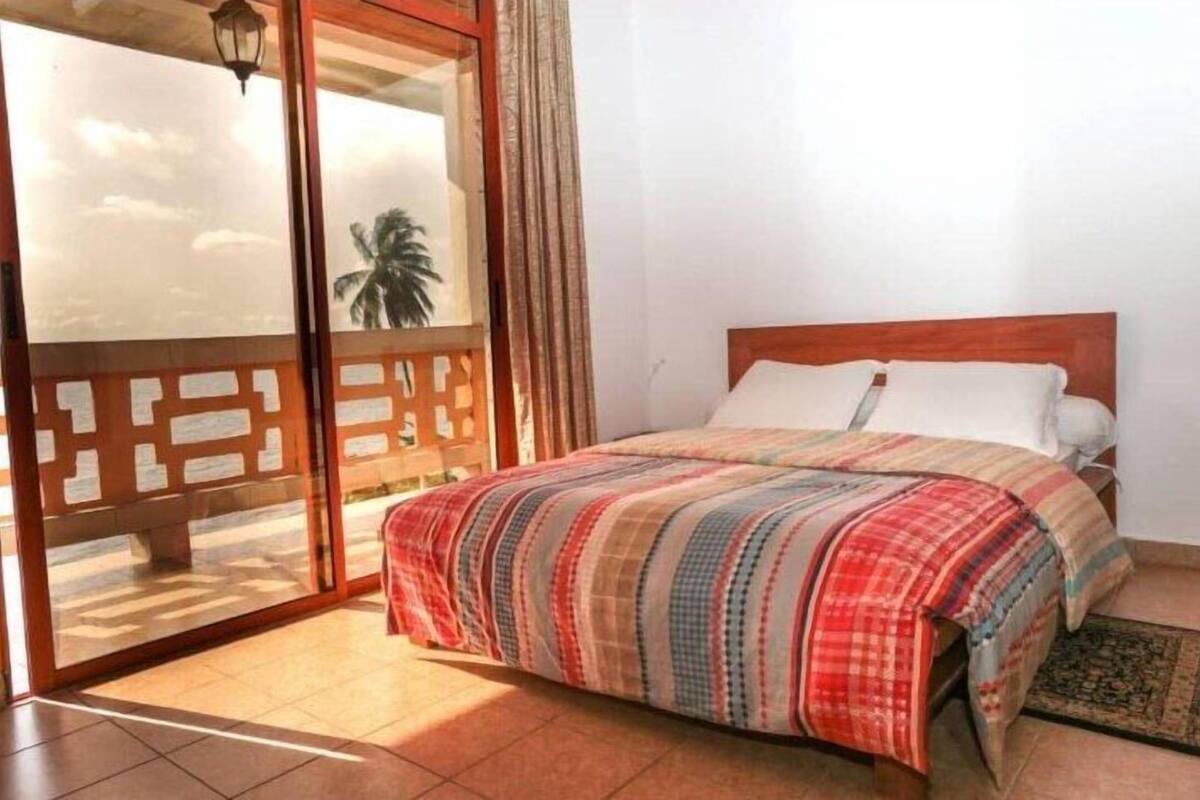 A bedroom with a bed, a window with a view, and a door leading to an outdoor area.