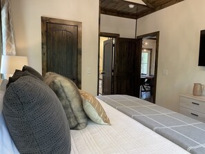 A bedroom with a bed, pillows, a dresser, and a mirror.