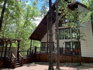 Escape to a serene forest retreat with a cozy cabin featuring large windows, a spacious deck, and a peaceful atmosphere.