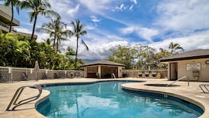 A swimming pool with a tiled deck, palm trees, and a covered seating area. - Maui Banyan G410 - Remodeled, Partial Ocean View, AC, Across Kamaole Beach! (Kihei)
