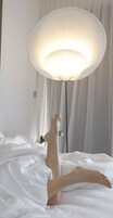 Un lit avec du linge de lit blanc et une grande lampe sur pied.