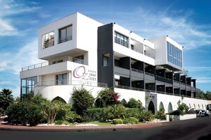Un hôtel moderne à la façade blanche, doté de nombreux balcons et d’un parking souterrain.