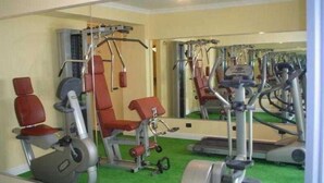 A gym with exercise equipment, a mirror, and green flooring. - Canali (Rapallo)