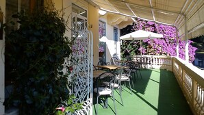 An outdoor café with tables and chairs, covered by a canopy, and surrounded by greenery and flowers. - Canali (Rapallo)