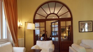 A room with two white sofas, a small wooden table, a floor lamp, and a large arched doorway leading to another room. - Canali (Rapallo)