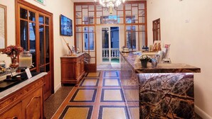 A hotel lobby with a patterned floor, a reception desk, a chandelier, and a view of the outside. - Canali (Rapallo)