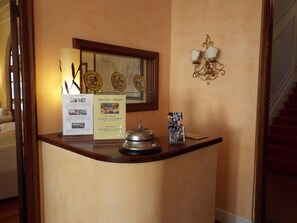 A reception desk with a framed picture, a sign, and a decorative wall lamp. - Canali (Rapallo)