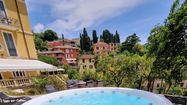 A hot tub on a stone patio with a view of surrounding buildings and trees. - Canali (Rapallo)