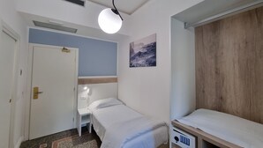 A small, neatly arranged bedroom with a single bed, a bedside table, a wardrobe, and a ceiling light. - Canali (Rapallo)