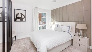 Una camera da letto moderna con un letto grande, un comodino con una lampada e un'opera d'arte astratta incorniciata a parete.