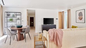 Un soggiorno moderno con divano, TV e zona pranzo con sedie e tavolo.