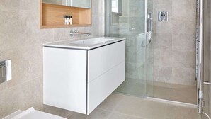 Un bagno moderno con cabina doccia in vetro, un mobile lavabo bianco con specchio e un angolo toilette separato.