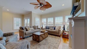 A spacious living room with a sectional sofa, a coffee table, and a large ceiling fan. - Paradise awaits! 7 Bedroom, Private Neighborhood Pool, Walk to the Beach! (Isle Of Palms)