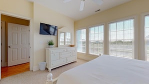 A bedroom with a bed, a dresser, a television, and large windows. - Paradise awaits! 7 Bedroom, Private Neighborhood Pool, Walk to the Beach! (Isle Of Palms)